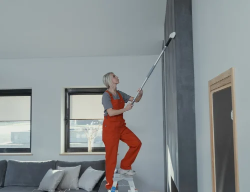 Professional cleaner dusting a high wall from a ladder in College Park, GA
